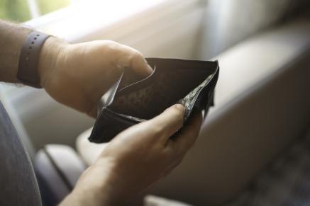 Homme qui regarde dans un portefeuille vide malgré la baisse des taux d'intérêts